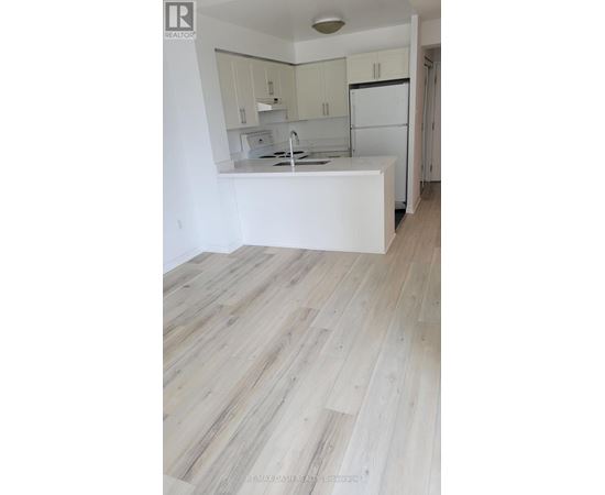 A kitchen with white cabinets and a white island with a sink.