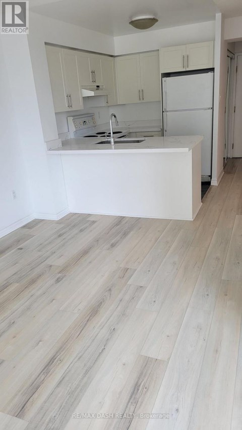 A kitchen with white cabinets and a white island with a sink.