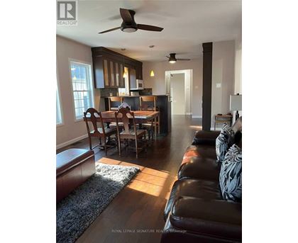 A living room with a brown leather couch and a dining table with chairs.