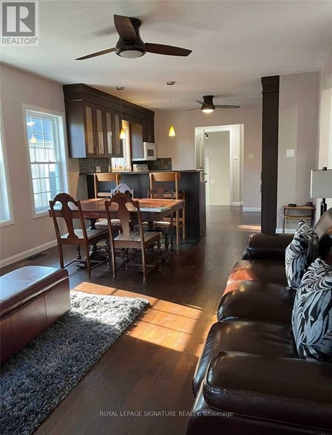 A living room with a brown leather couch and a dining table with chairs.