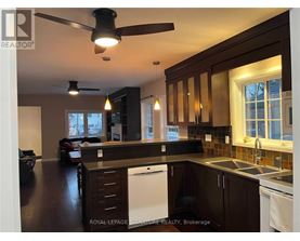 A kitchen with dark wood cabinets and a white dishwasher.