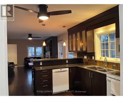 A kitchen with dark wood cabinets and a white dishwasher.