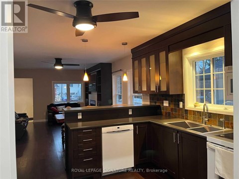 A kitchen with dark wood cabinets and a white dishwasher.