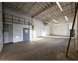 A large, empty warehouse with a concrete floor and white walls.