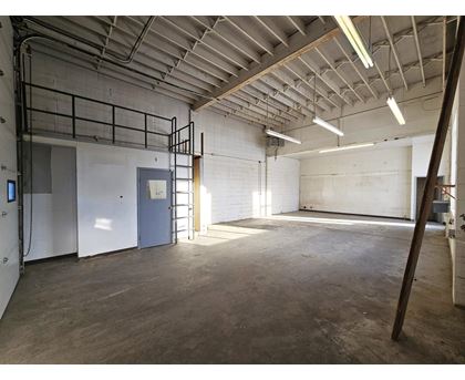 A large, empty warehouse with a concrete floor and white walls.