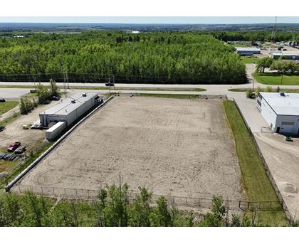 An aerial view of a large, empty parking lot surrounded by buildings and trees.