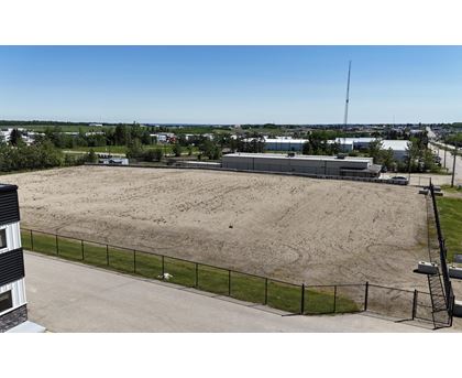 A large, empty field with a fence and a building in the background.