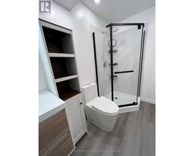 A white toilet in a bathroom with a walk-in shower.