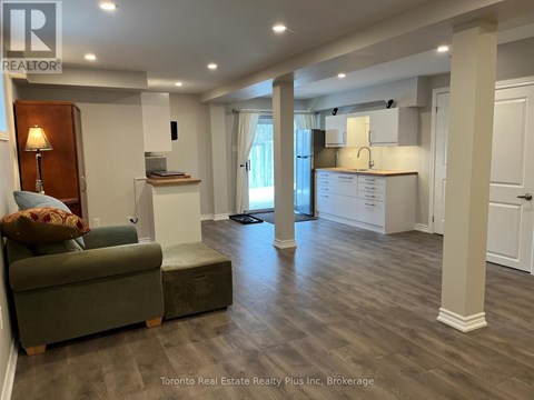 A well-lit, spacious living room with a green couch and a wooden floor.