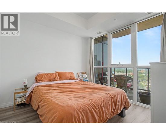 A bedroom with a bed and a window overlooking a cityscape.
