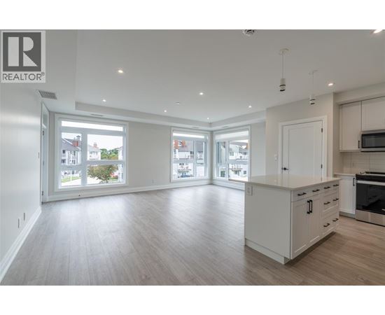A spacious kitchen with white cabinets and a wooden floor.