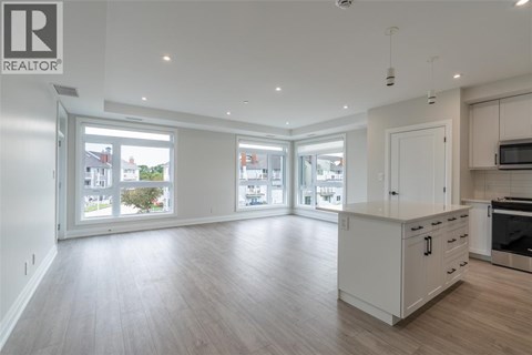 A spacious kitchen with white cabinets and a wooden floor.