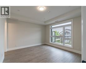 A spacious room with a large window and wooden flooring.