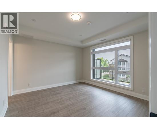 A spacious room with a large window and wooden flooring.