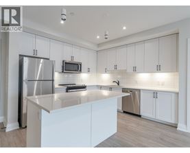 A modern kitchen with white cabinets and a stainless steel refrigerator.