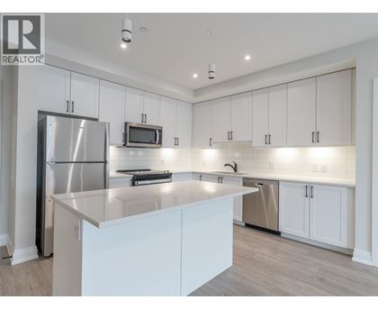 A modern kitchen with white cabinets and a stainless steel refrigerator.