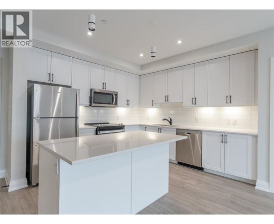 A modern kitchen with white cabinets and a stainless steel refrigerator.