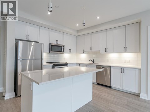 A modern kitchen with white cabinets and a stainless steel refrigerator.