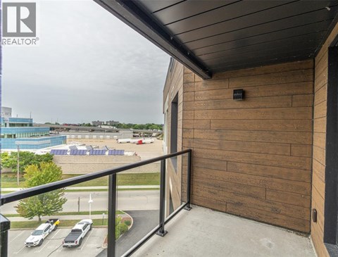 A balcony with a view of a parking lot and a pool.