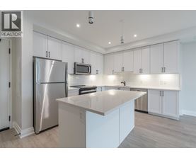 A modern kitchen with white cabinets and a stainless steel refrigerator.