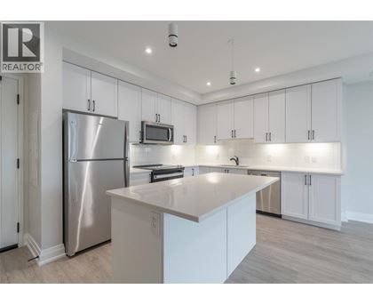 A modern kitchen with white cabinets and a stainless steel refrigerator.