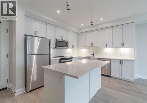 A modern kitchen with white cabinets and a stainless steel refrigerator.
