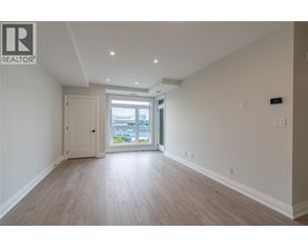 A spacious room with light wood flooring and white walls.