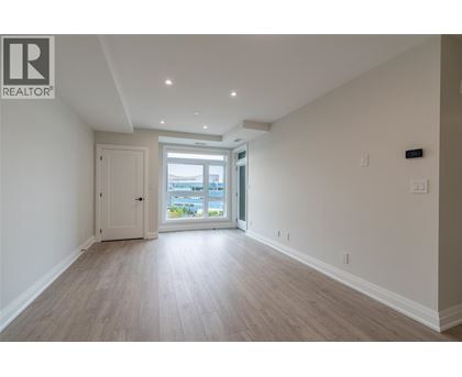 A spacious room with light wood flooring and white walls.