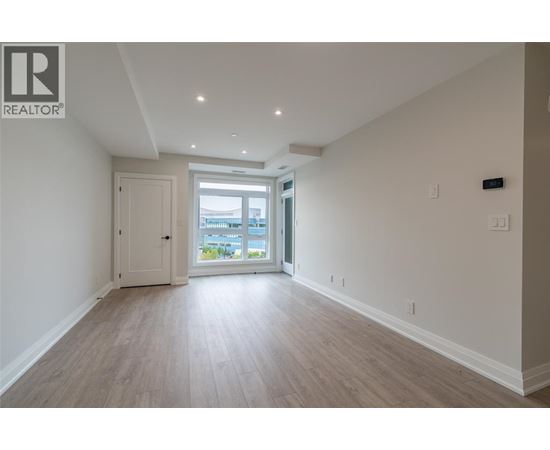 A spacious room with light wood flooring and white walls.