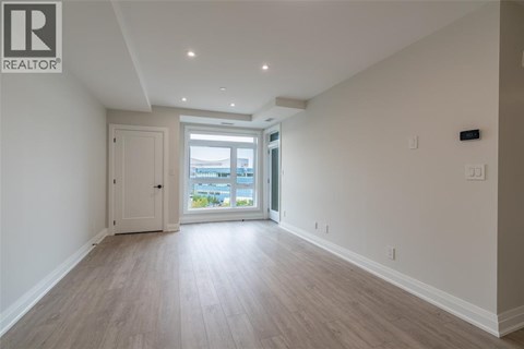 A spacious room with light wood flooring and white walls.
