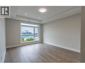 A spacious room with wooden flooring and a large window overlooking a cityscape.