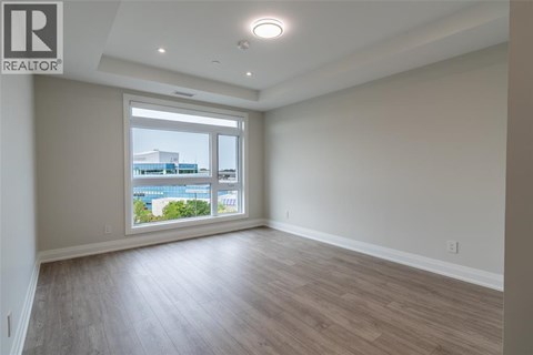 A spacious room with wooden flooring and a large window overlooking a cityscape.