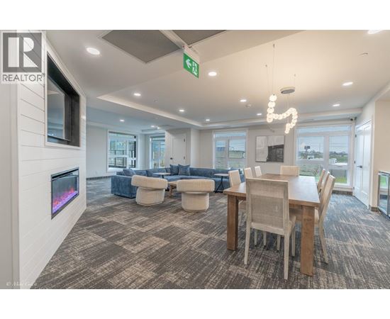 A living room with a grey carpet and a wooden dining table.