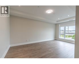 A spacious room with wooden flooring and a large window.