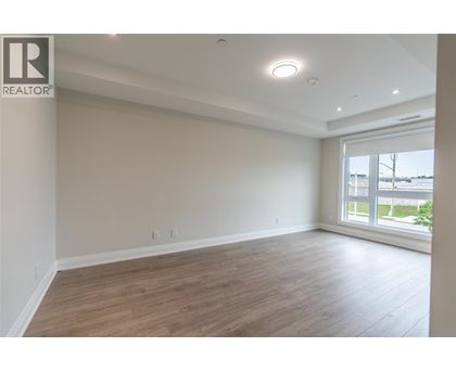 A spacious room with wooden flooring and a large window.