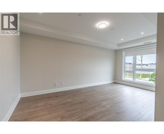 A spacious room with wooden flooring and a large window.