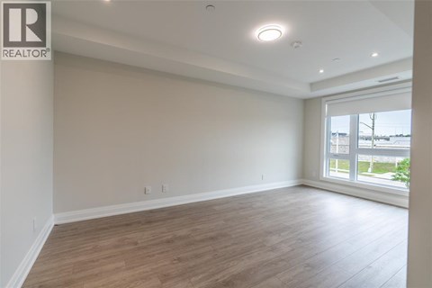 A spacious room with wooden flooring and a large window.