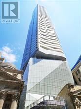A tall building with a curved glass facade stands in front of an older building.