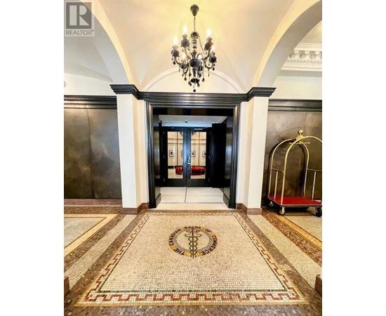 A hallway with a chandelier, a trolley, and a mosaic floor.