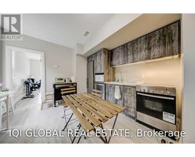 A modern kitchen with a wooden table and stainless steel appliances.