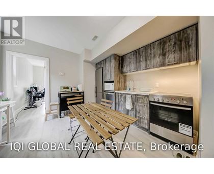 A modern kitchen with a wooden table and stainless steel appliances.