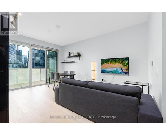 A living room with a grey couch and a painting on the wall.