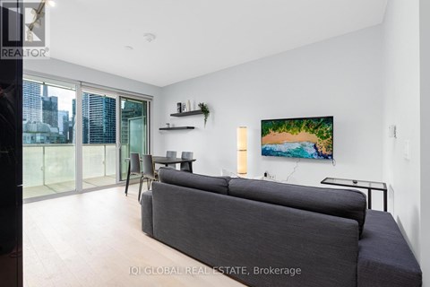 A living room with a grey couch and a painting on the wall.