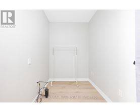 A white bedroom with a bed frame and a hose on the floor.