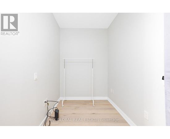A white bedroom with a bed frame and a hose on the floor.