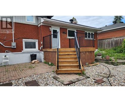 A red brick house with a wooden staircase leading to the front door.