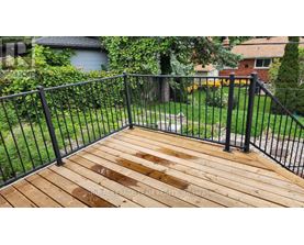 A wooden deck with a black railing.
