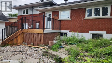 A red brick house with a black railing and a small garden in front.