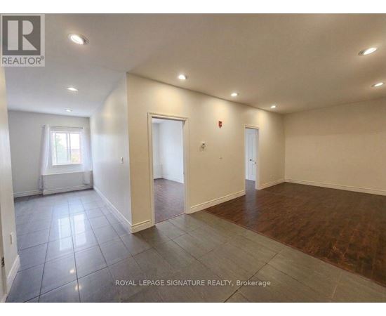 A spacious room with wooden flooring and white walls.