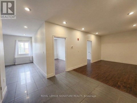 A spacious room with wooden flooring and white walls.